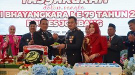 Kapolres Jombang AKBP Ardi Kurniawan memberikan potongan tumpeng kepada Kompol Bambang Setyobudi dalam acara Tasyakuran Hari Bhayangkara ke-79. (Foto: dok)