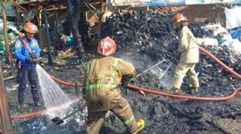 Petugas sedang melakukan pembasahan di area gudang rongsok di Johowinong, Kec Mojoagung, Jombang yang terbakar.