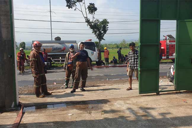 Petugas sedang melakukan pembasahan di areal gudang serbuk kayu yang terbakar. Lokasinya, di Desa Rejoslamet, Kecamatan Mojowarno, Jombang.